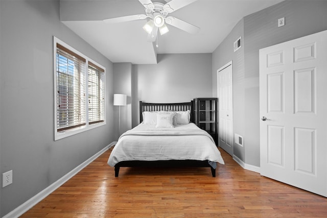 bedroom with baseboards, a closet, visible vents, and wood finished floors