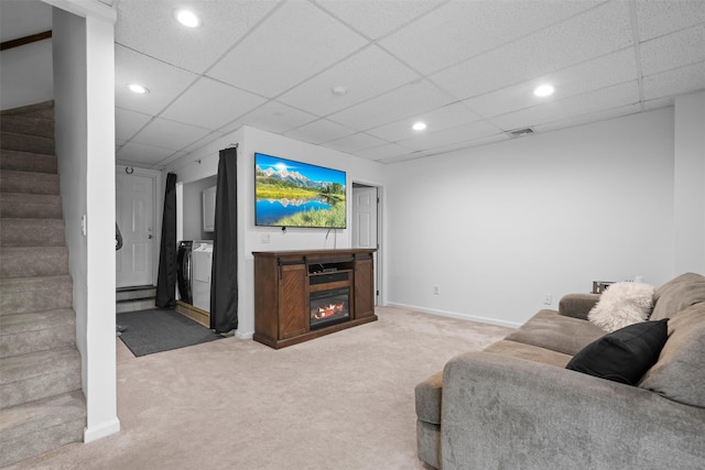 living room with stairway, a glass covered fireplace, carpet flooring, a drop ceiling, and baseboards