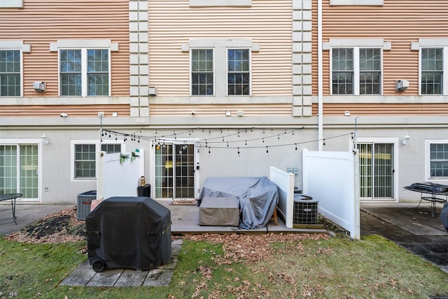 rear view of property featuring a patio, central air condition unit, and stucco siding