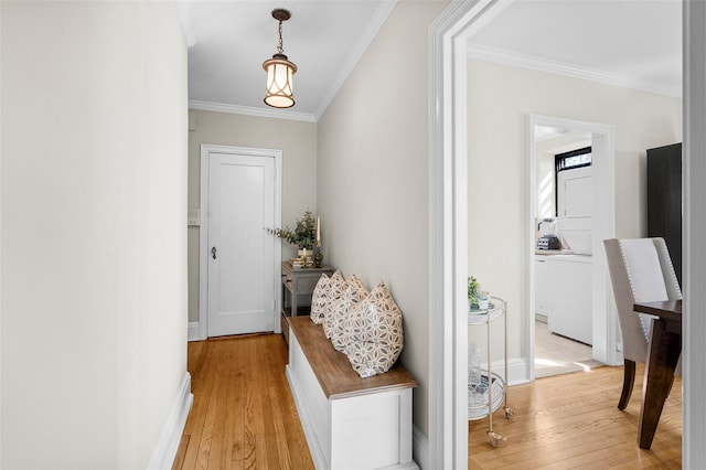 doorway with light wood-style floors, stacked washer / dryer, and ornamental molding