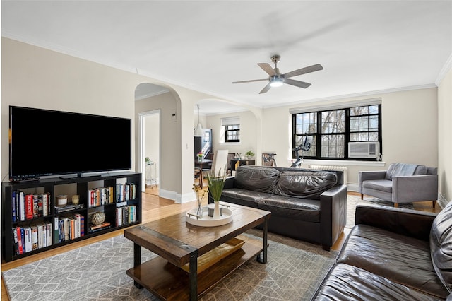 living room with cooling unit, crown molding, arched walkways, and wood finished floors