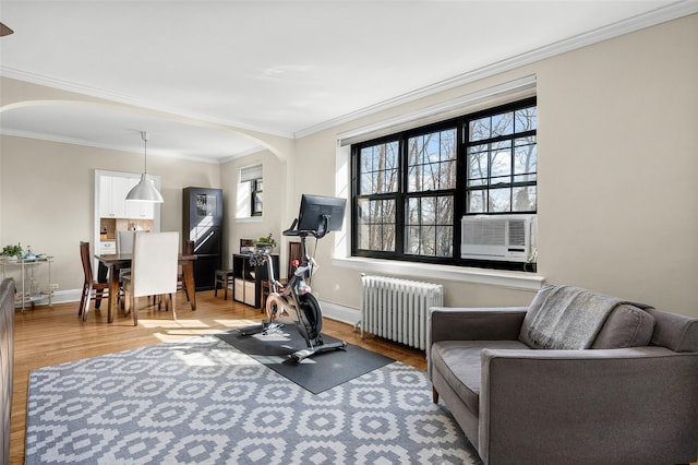 workout room featuring arched walkways, baseboards, radiator heating unit, cooling unit, and light wood-style floors