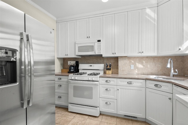 kitchen with white appliances, crown molding, white cabinetry, and a sink