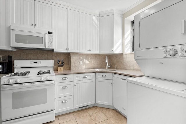 kitchen featuring white appliances, a sink, white cabinetry, light countertops, and stacked washer and clothes dryer