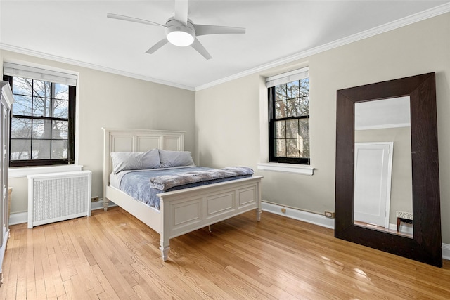 bedroom with radiator heating unit, multiple windows, ornamental molding, and light wood-style flooring