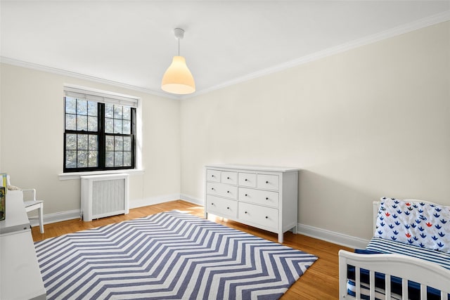 bedroom with baseboards, light wood finished floors, crown molding, and radiator