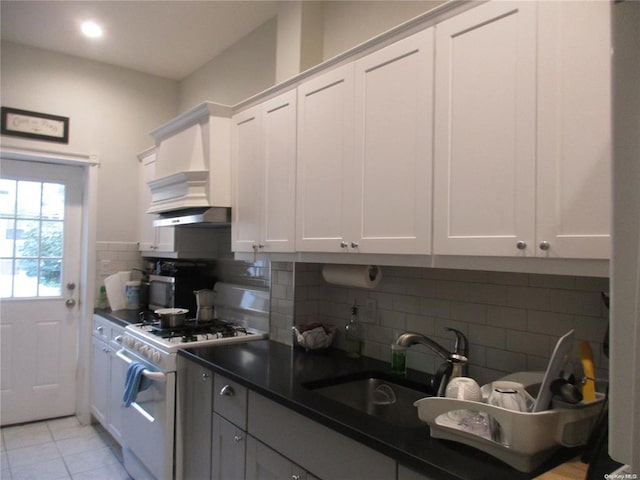 kitchen featuring tasteful backsplash, a sink, dark countertops, gas range gas stove, and custom exhaust hood