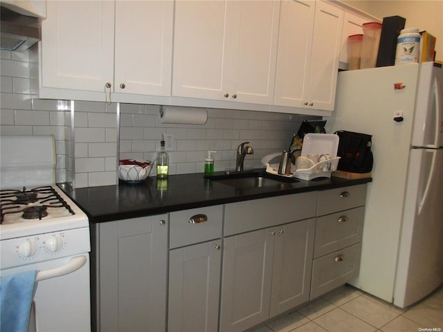 kitchen with dark countertops, white appliances, decorative backsplash, and a sink