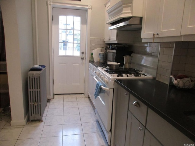 kitchen featuring tasteful backsplash, radiator, dark countertops, and white gas range