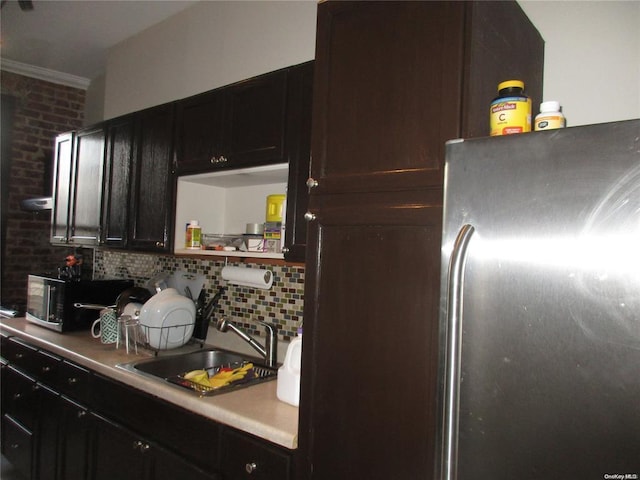 kitchen featuring a sink, decorative backsplash, open shelves, ornamental molding, and freestanding refrigerator