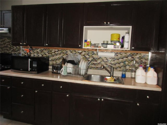 kitchen with black microwave, backsplash, light countertops, and a sink