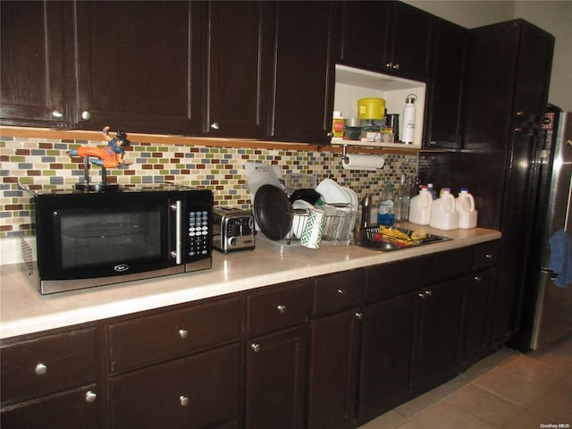 kitchen with tasteful backsplash, black microwave, light tile patterned flooring, and light countertops