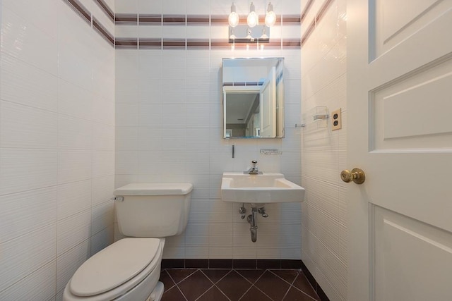 half bathroom with a sink, tile walls, toilet, and tile patterned floors