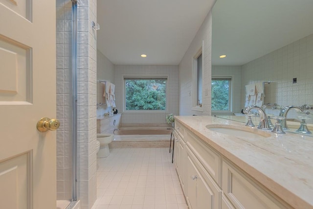 bathroom with toilet, tile walls, vanity, tile patterned flooring, and a bath