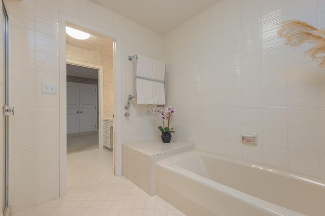 bathroom with vanity, tile walls, a bath, and tile patterned floors