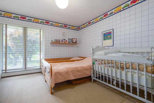 bedroom featuring a baseboard heating unit, tile walls, and carpet floors