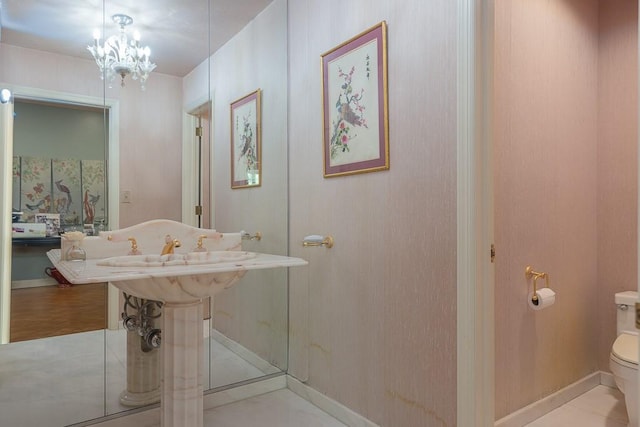 bathroom with a notable chandelier, baseboards, and toilet