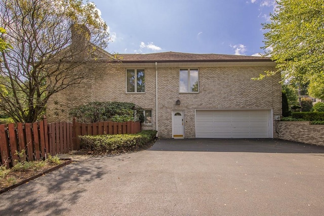 view of front of home with fence, brick siding, driveway, and a garage