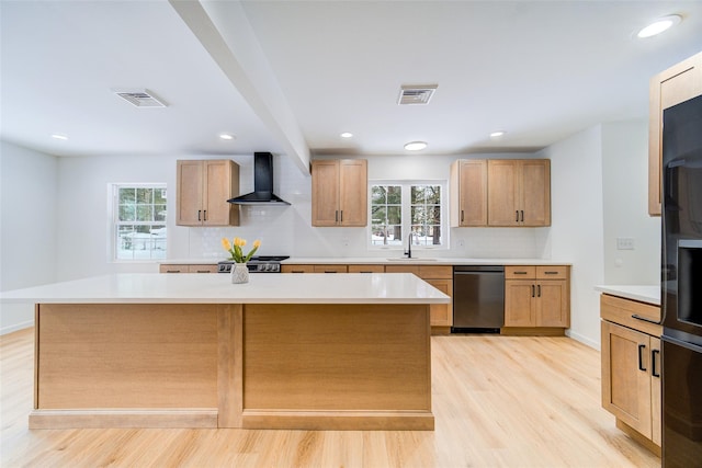 kitchen with a center island, light countertops, visible vents, dishwasher, and wall chimney exhaust hood