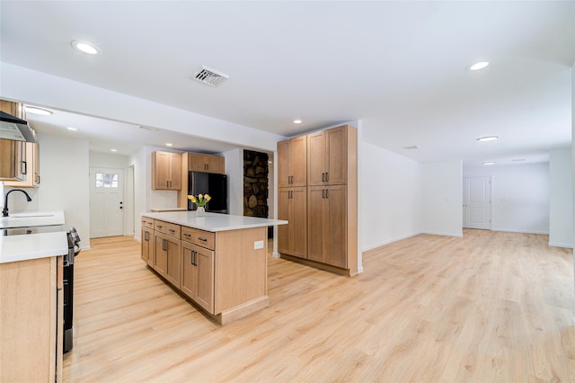 kitchen featuring visible vents, a center island, freestanding refrigerator, light countertops, and range with electric stovetop