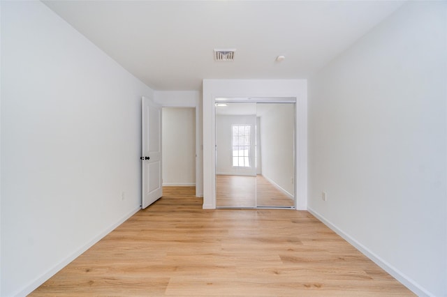 spare room with baseboards, visible vents, and light wood-style floors