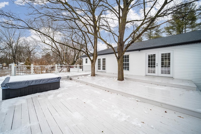 snow covered deck with a hot tub and french doors