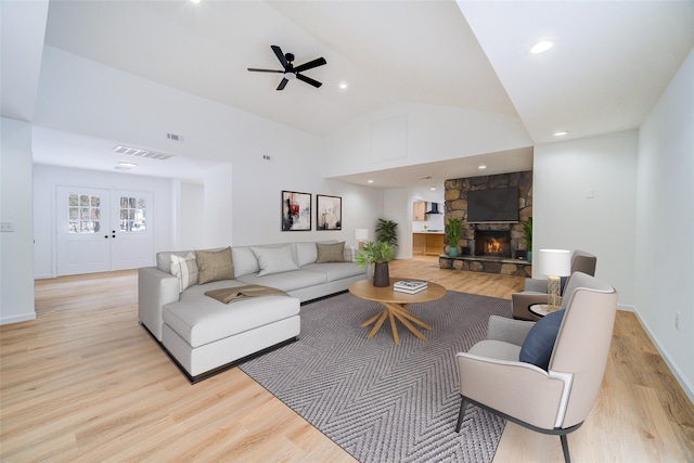 living area featuring high vaulted ceiling, visible vents, a fireplace, and light wood finished floors