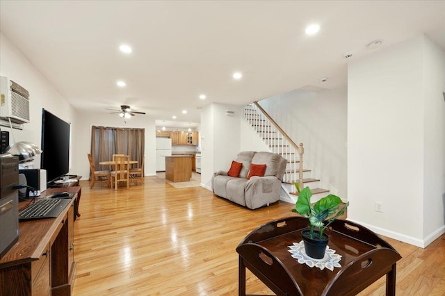 living room featuring light wood-type flooring, baseboards, recessed lighting, stairs, and ceiling fan