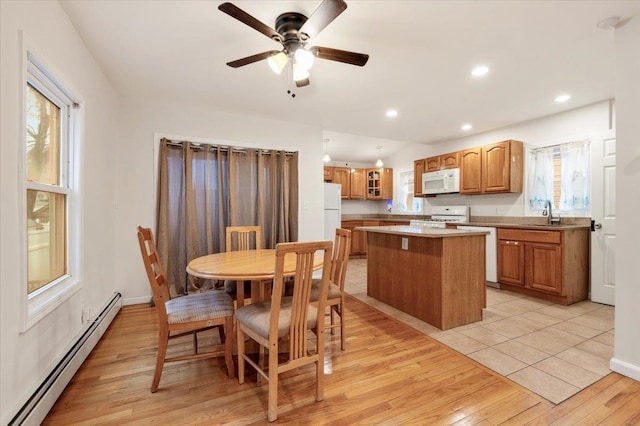 dining space with a baseboard radiator, light wood-type flooring, ceiling fan, and plenty of natural light