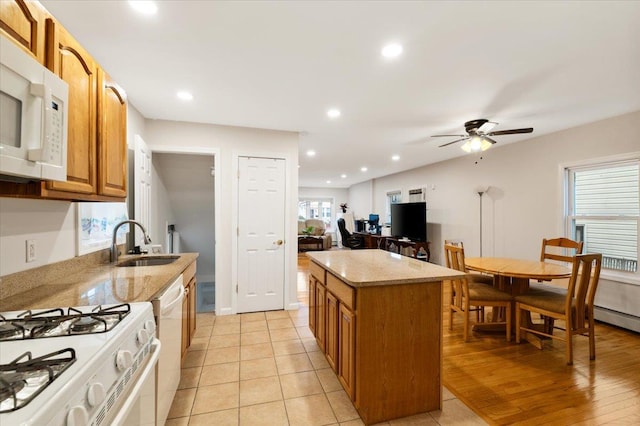 kitchen featuring a ceiling fan, white appliances, a sink, and light stone counters