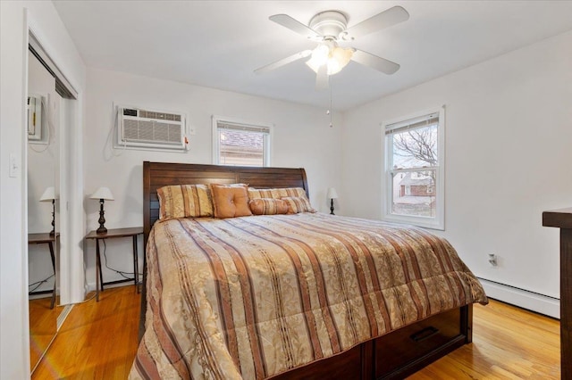bedroom with light wood-type flooring, ceiling fan, an AC wall unit, and a baseboard radiator