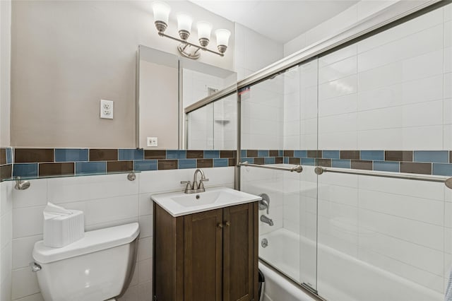 bathroom with bath / shower combo with glass door, vanity, toilet, and tile walls