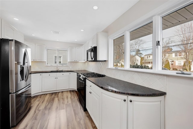 kitchen featuring black appliances, tasteful backsplash, light wood-style flooring, and white cabinetry