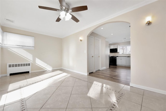 empty room with arched walkways, radiator, light tile patterned flooring, and baseboards