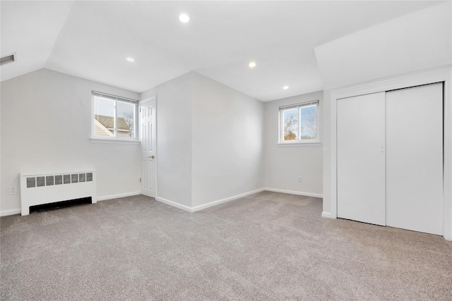 additional living space with visible vents, baseboards, light colored carpet, radiator, and lofted ceiling