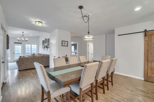 dining space featuring a barn door, light wood-type flooring, recessed lighting, and baseboards