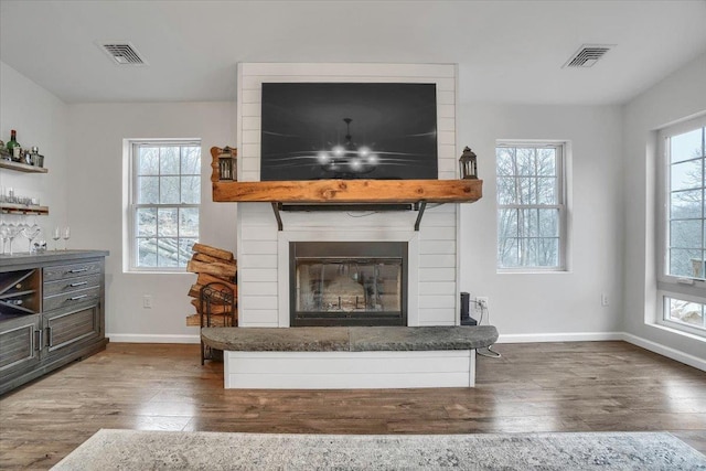 living room with dark wood-type flooring, visible vents, and a fireplace