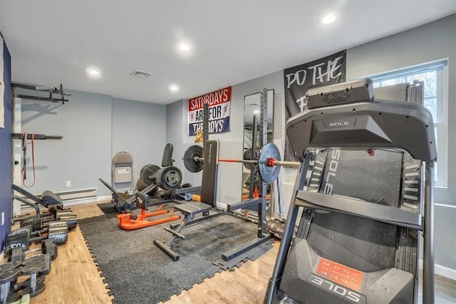 exercise area featuring recessed lighting, a baseboard heating unit, wood finished floors, visible vents, and baseboards