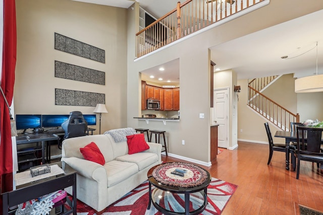 living area with stairs, visible vents, a high ceiling, baseboards, and hardwood / wood-style flooring