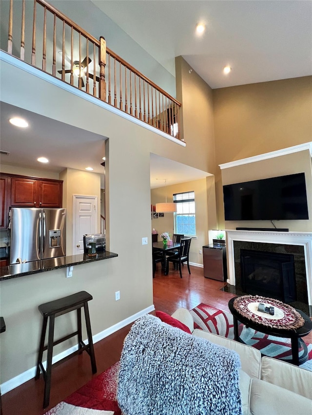 living room with dark wood-style flooring, recessed lighting, a towering ceiling, and baseboards