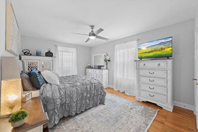 bedroom featuring ceiling fan, light wood-style flooring, and baseboards