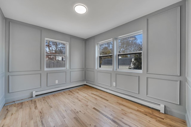 empty room with a baseboard radiator, light wood-style flooring, and a decorative wall