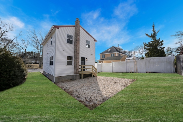 rear view of property featuring a chimney, fence, and a lawn