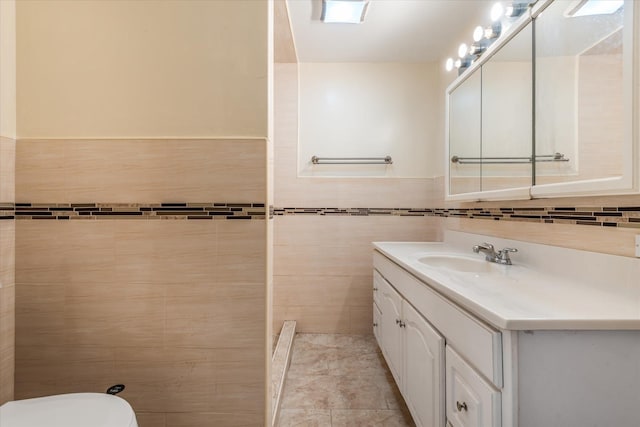 bathroom with tile walls, tile patterned flooring, vanity, and toilet