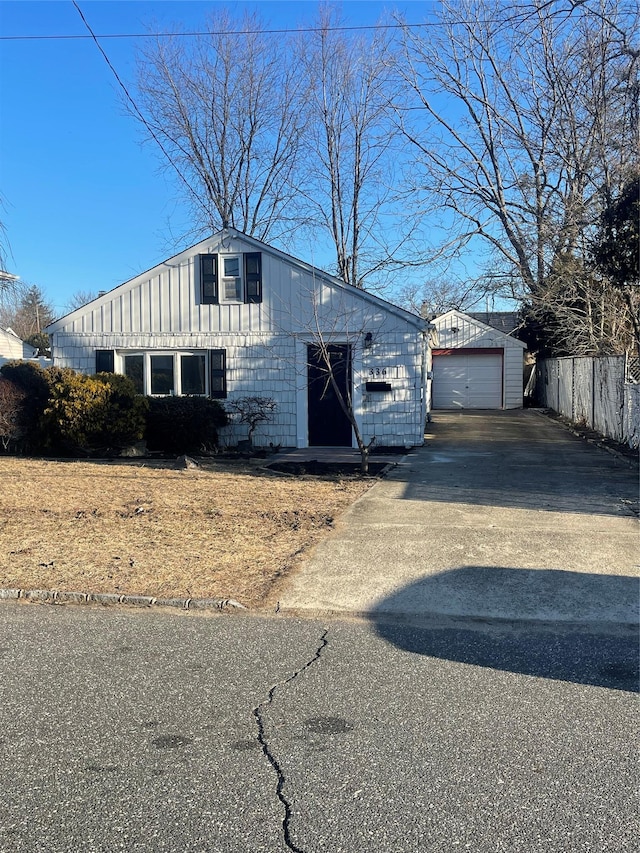 view of front facade with an outbuilding, a detached garage, fence, driveway, and board and batten siding