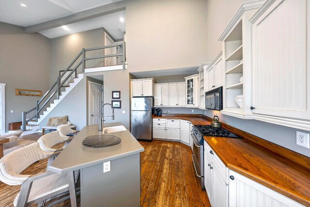 kitchen with appliances with stainless steel finishes, white cabinetry, glass insert cabinets, and a sink