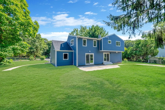 back of property with entry steps, a lawn, a patio area, and fence