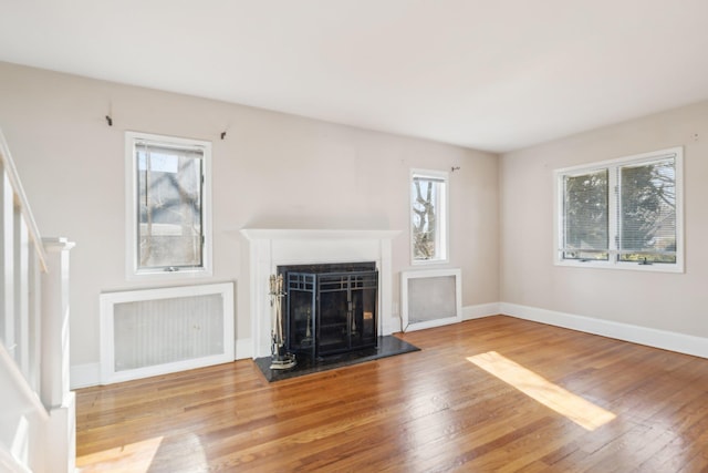 unfurnished living room with stairs, a fireplace, baseboards, and wood finished floors