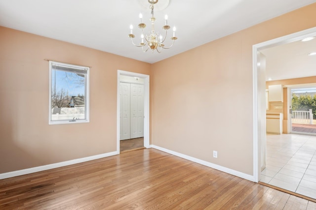 interior space with baseboards, light wood finished floors, and an inviting chandelier