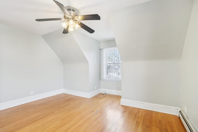 additional living space with baseboards, ceiling fan, wood finished floors, vaulted ceiling, and a baseboard heating unit